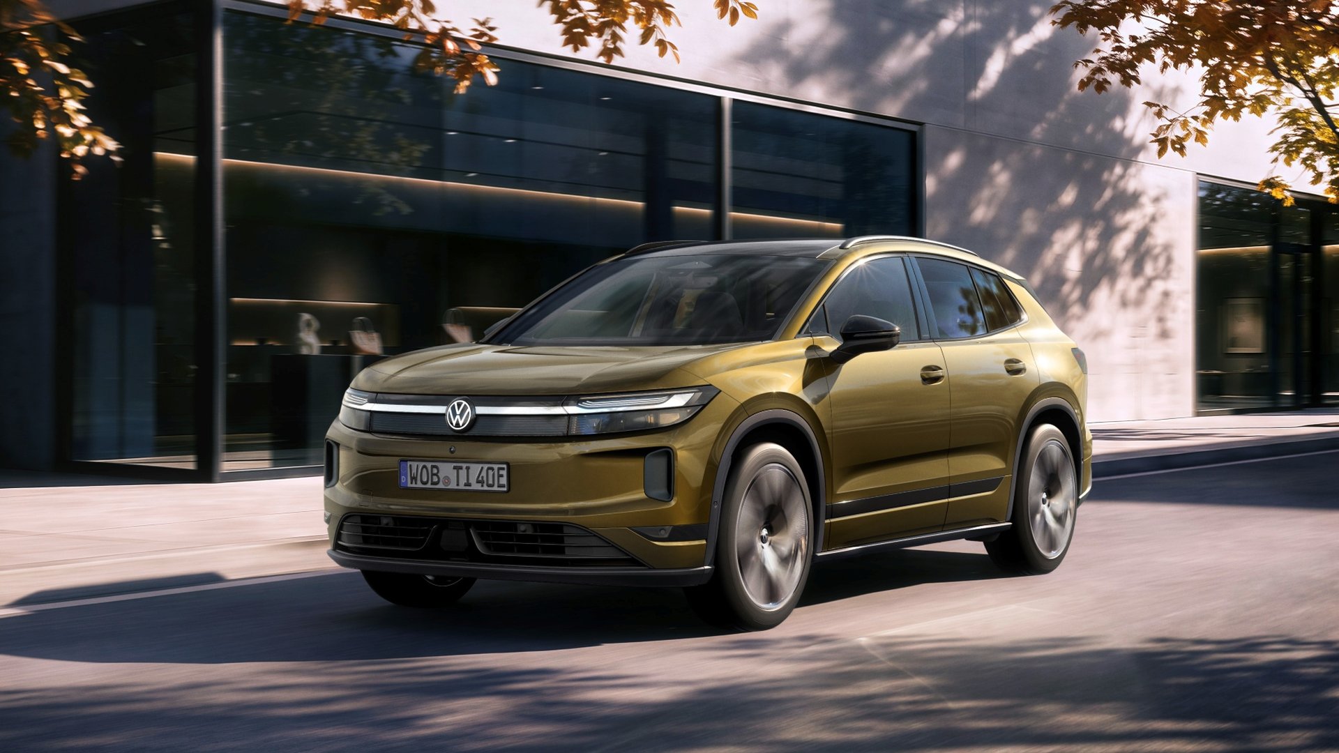 Χρυσό Volkswagen ID. Tiguan σε εμπρός τριών τετάρτων λήψη μπροστά από σύγχρονο κτίριο